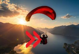 Paraglider sails over lake and mountaints